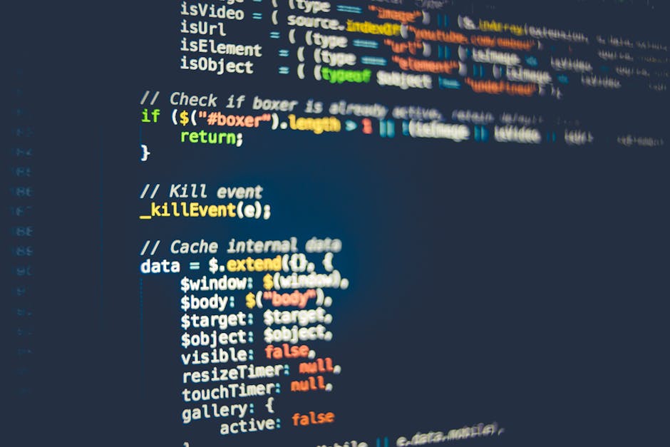 Close-up image of a computer monitor displaying colorful lines of programming code, including syntax highlighting with pink, blue, yellow, and white text. The screen is slightly angled, revealing a da